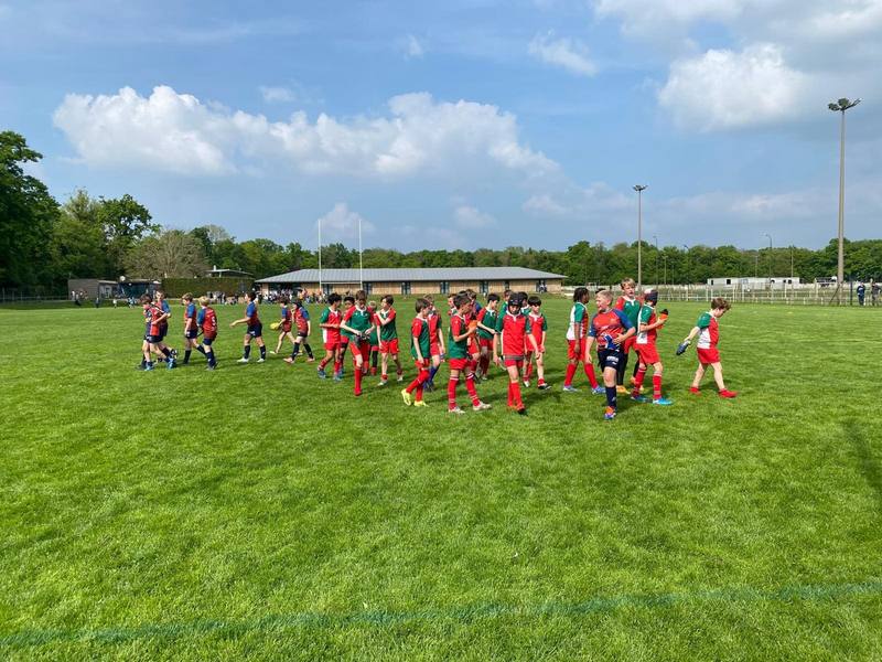 Les U12 en maillots rouge et vert sur un grand terrain ensoleillé, lors d'un plateau.